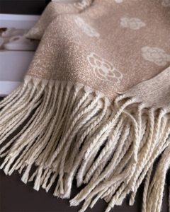 Detailed close-up of camellia pattern jacquard fabric and fringe on camel winter scarf