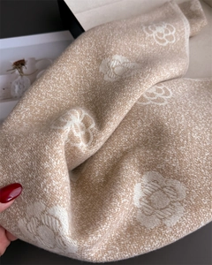Detail of beige cashmere scarf featuring camellia floral patterns and twill weave texture
