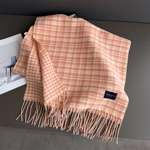 Close-up of pink and beige plaid scarf with fringe tassels and elegant brand label
