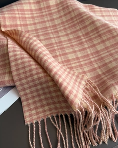 Close-up of pink and cream plaid scarf with long fringe detail and soft cashmere-like texture