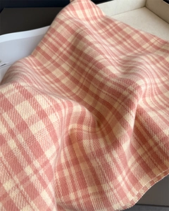 Close-up of pink and white plaid scarf showing soft cashmere texture and fine tassels