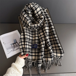 Close-up of black and white plaid scarf with tassels and an elegant label detail