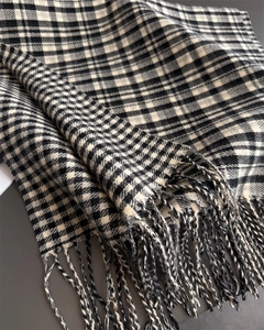 Close-up of classic black and white plaid scarf featuring soft texture and fringe edges