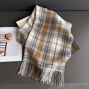 Detail of soft plaid scarf with long fringe tassels in grey and beige on a stylish tray