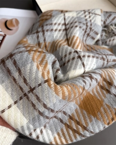 Close-up of gray and orange plaid scarf texture with soft tassels and woven details