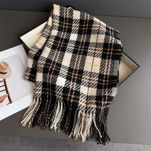 Detail of classic plaid scarf with fringe in black and cream stored in a gift box