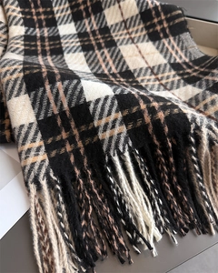 Macro view showing the soft woven texture and fine fringe of the plaid cashmere scarf