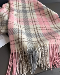 Detail of pink and grey plaid scarf showing soft cashmere texture and twisted tassels