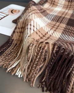 Detail view of the soft cashmere-like texture and long tassel fringe on the plaid scarf