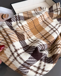 Detailed view of thick plaid scarf in coffee and beige tones inside a gift box