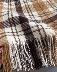 Close-up detail of soft plaid scarf texture with classic woven tassels in neutral tones