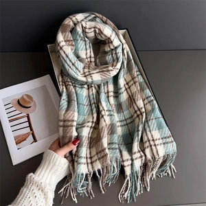 Close-up of knit plaid scarf with fringe tassels in a luxury black gift box display