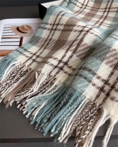 Detailed view of plaid pattern and soft tassel edges on a warm cashmere-feel scarf