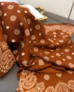 Detailed view of caramel brown paisley scarf showing refined twill texture and drape