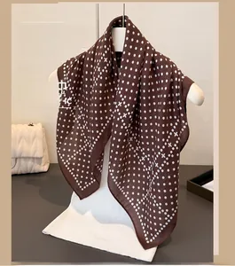 Detail of brown square scarf featuring white polka dots and cross pattern on chiffon fabric
