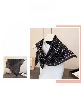 Close-up of lightweight black silk scarf with white polka dots on a white mannequin