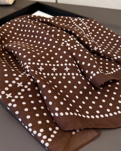 Close-up of brown silk scarf showing white polka dot and cross patterns with smooth texture