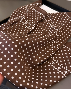 Detailed view of the brown silk scarf fabric with white polka dots and cross pattern