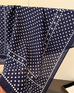 Detail of navy blue polka dot scarf showing soft translucent linen-feel fabric texture