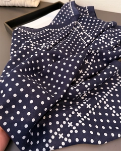Close-up of navy blue fabric with white polka dots and delicate twill weaving texture