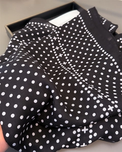 Close-up of black silk scarf with white polka dot pattern and fine twill texture