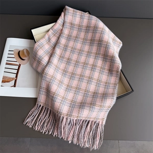 Détail d'une écharpe à carreaux rose et gris aspect cachemire avec franges sur plateau