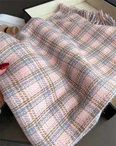 Gros plan d'une écharpe en cachemire à carreaux rose et gris avec des franges douces