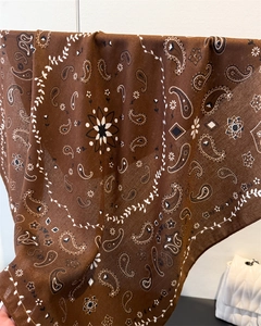 Detail of coffee paisley silk scarf showing intricate floral patterns and soft texture