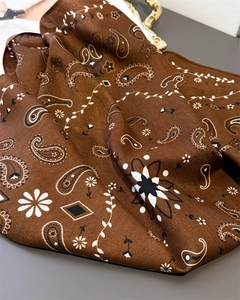 Detail of silk-feel scarf featuring classic brown paisley patterns and smooth satin texture