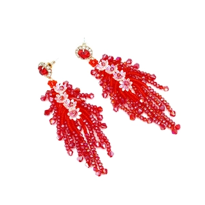 Detail of red crystal fringe earrings with floral beadwork and golden settings