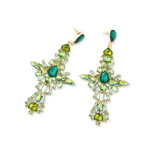 Detailed close-up of gold cross earrings with sparkling green rhinestones and crystals