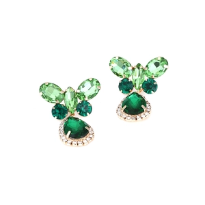 Macro detail of vintage emerald green rhinestone earrings with butterfly drop accents