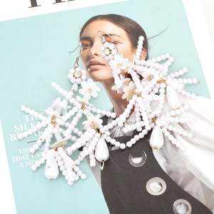 Bohemian white pearl flower tassel earrings with crystals on a fashion magazine background