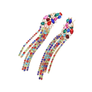 Détail macro de boucles d'oreilles à pompons longs avec strass colorés et fleurs en cristal