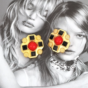 Baroque style gold-tone earrings with red resin stones on a fashion magazine background