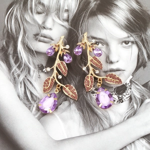 Golden branch earrings with purple crystals and pink diamonds on a fashion background