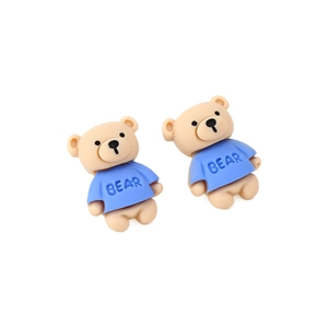 Boucles d'oreilles ours en résine marron avec t-shirt bleu sur fond blanc épuré