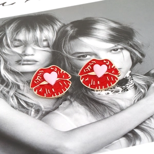 Boucles d'oreilles lèvres rouges et cœur avec bordure dorée sur fond de mode