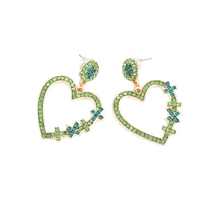 Détail de boucles d'oreilles cœur en alliage doré avec strass verts et bleus et motif croix