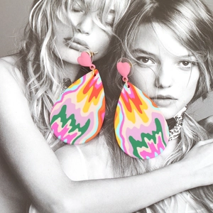Pink heart studs with colorful wavy teardrop pendants on a fashion magazine background