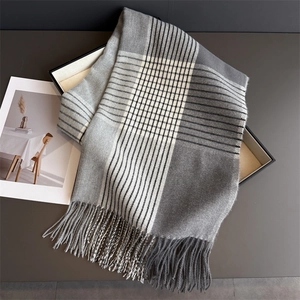 Detail shot of a grey checkered scarf with soft fringe trim on a minimalist tray