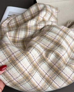 Gros plan d'une écharpe à carreaux beige et marron montrant le tissage sergé et la texture