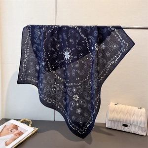 Elegant navy paisley cotton linen scarf displayed on a silver metal rack with a white bag