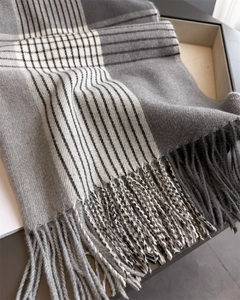 Close-up of the grey and beige plaid scarf with soft cashmere texture and fringe tassels