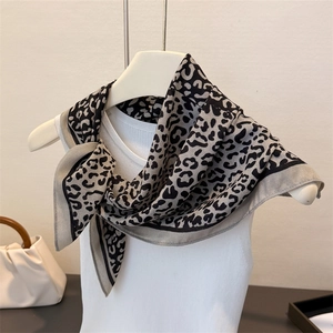 Detail view of leopard print scarf draped on mannequin showing silky texture and pattern