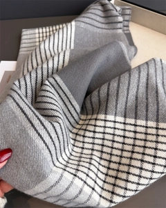 Detail of soft knit texture on grey and beige plaid scarf with fringed edges
