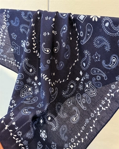 Close-up of navy blue scarf featuring white paisley patterns and linen texture fabric