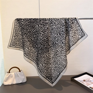 Elegant leopard print square scarf with black borders, displayed in a stylish setting