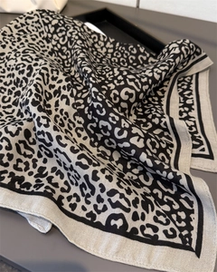 Detailed close-up of leopard print fabric texture and black striped border on a silk scarf