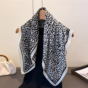 Detail of a black and white leopard print scarf draped on a wooden hanger with soft texture